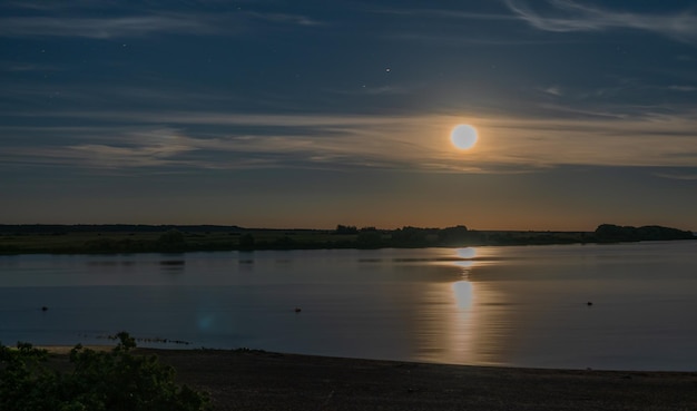 Moonrise over the river in the starry sky in light clouds. Night landscape