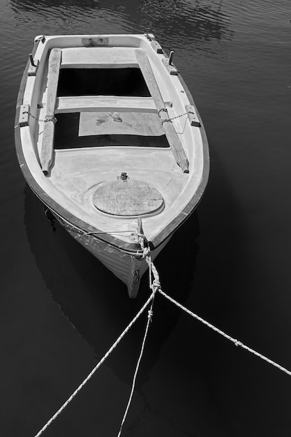 Пришвартованная старая деревянная весельная лодка. Черно-белая фотография