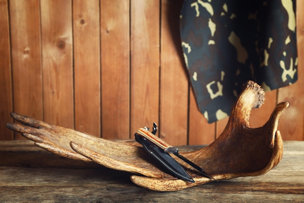 Photo moose antler with hunting knives on wooden background