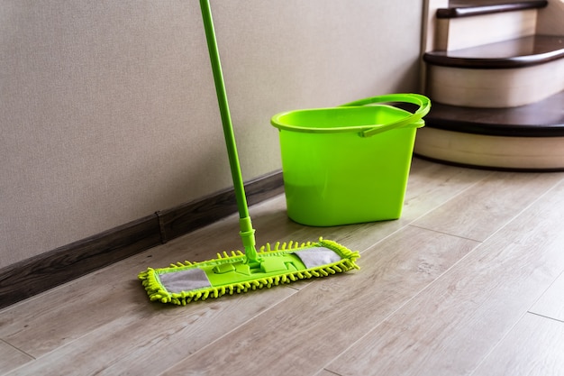 Mop with green microfiber rag, green plastic handle and bucket. Housekeeping concept.