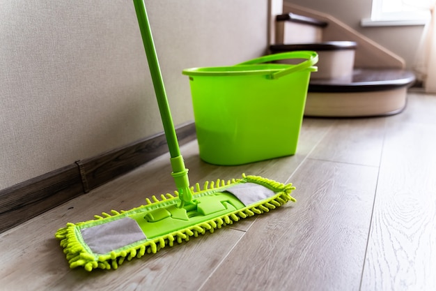 Mop with green microfiber rag, green plastic handle and bucket. Housekeeping concept.