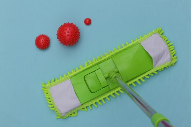 Mop with virus strain model on a blue background. The concept of cleaning the house, disinfection. Top view, studio shot.