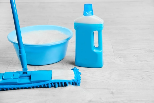 Mop in microfibra bagnata blu con detergente kit di disinfezione per la pulizia su un pavimento bianco isolato concetto di pulizia