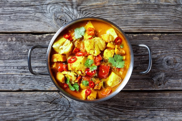 Moqueca Baiana Braziliaanse zeevruchten vis curry met witte vis kokosmelk verschillende groenten en verse koriander in een pot op een oude rustieke tafel horizontale weergave van bovenaf plat lag vrije ruimte close-up