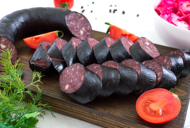 Morcilla - bloedworst. Stukken van Spaanse bloedworst op een houten scherpe raad op witte lijst.