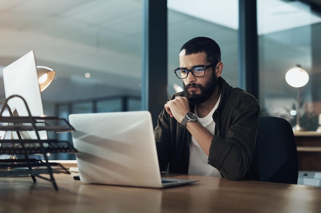 The more you focus the quicker youll find the solution Shot of a young businessman using a laptop during a late night in a modern office