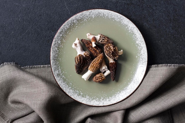 Morel mushrooms on a plate on black background