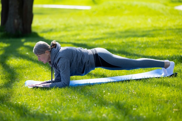 Morgenyoga Vrouw in grijze sportkleding doet yoga in het park