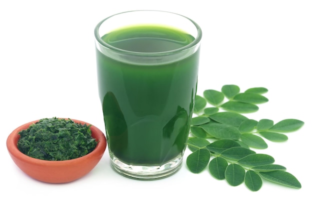 Moringa bladeren met extract in een glas op witte achtergrond