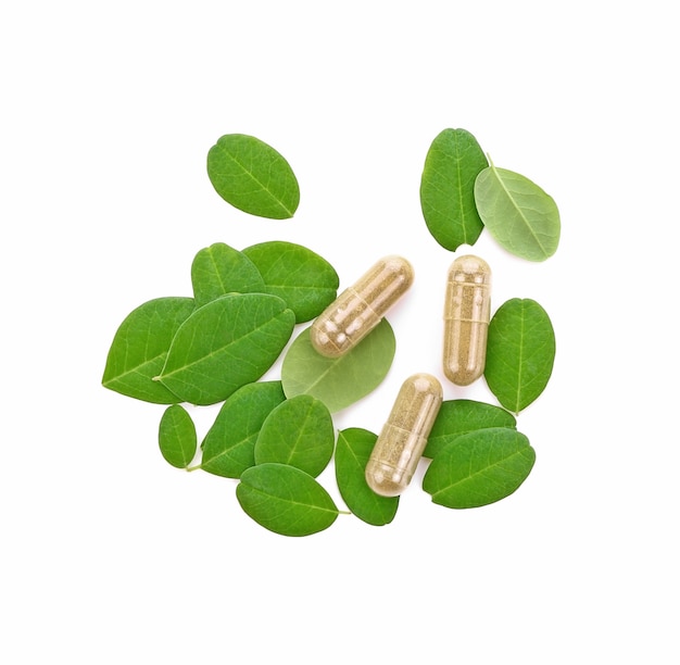 Moringa oleifera capsule met groene verse bladeren op witte achtergrond