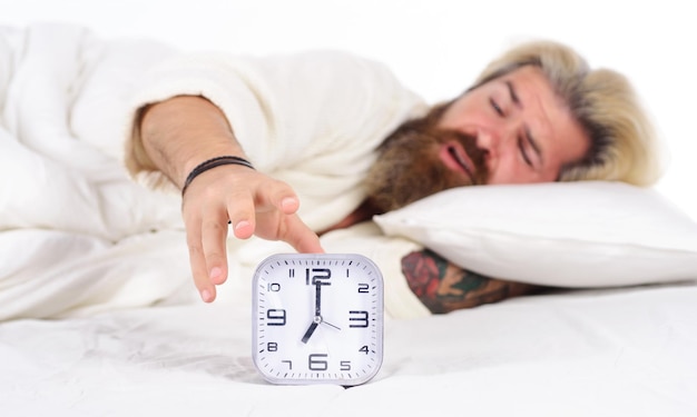 Morning awakening sleepy bearded man turning off alarm clock\
male in bed early wake up insomnia