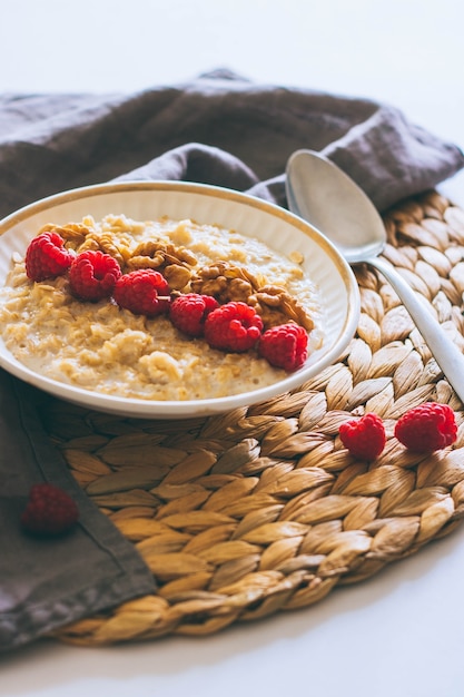 Morning breakfast, oatmeal in milk with raspberries and walnuts