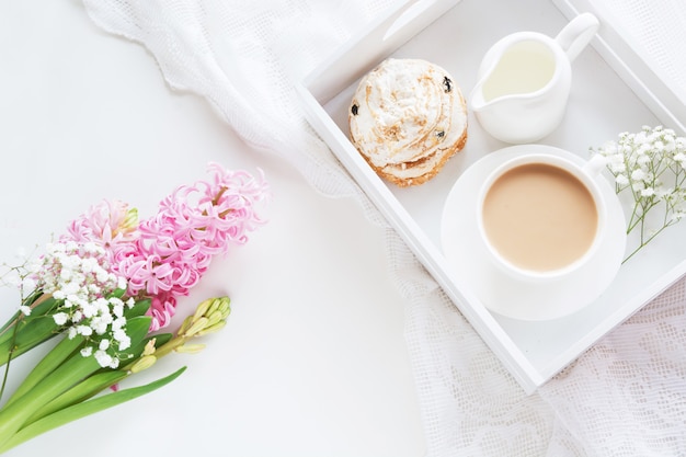 Morning breakfast in spring with a cup of black coffee with milk and pastries in the pastel colors