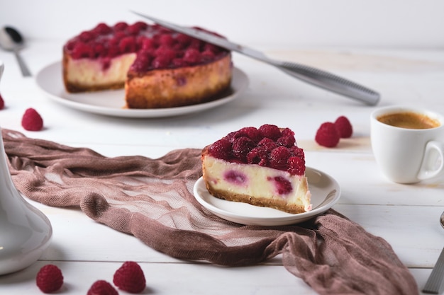 Morning breakfast with espresso and raspberry cheesecake. Slice of dessert on a plate and coffee.