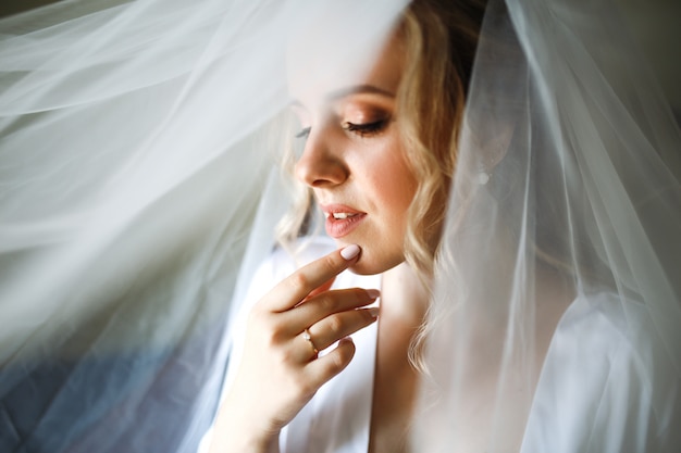 Morning of the bride. Beautiful bride in white wedding dress with bridal bouquet at wedding morning.