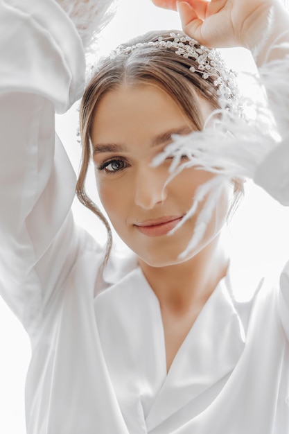 Morning of bride before the wedding Beautiful young woman with long veil in a white robe Natural beauty and professional makeupGirl in white lace boudoir dress
