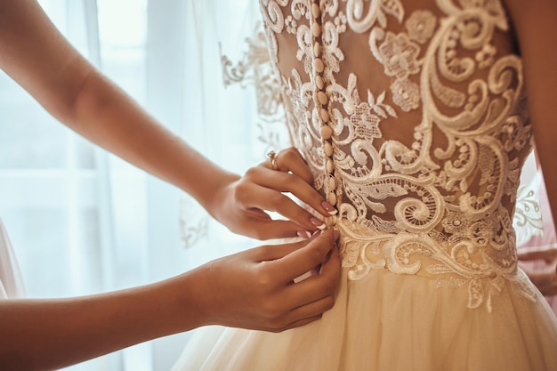 Morning of the bride when she wears a beautiful dress woman getting ready before wedding ceremony