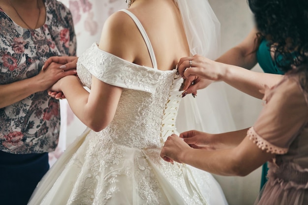 Mattina della sposa quando indossa un bellissimo vestito da donna che si prepara prima della cerimonia nuziale