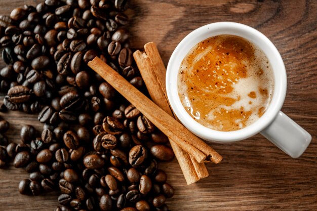 Morning coffee Coffee cup cinnamon and coffee beans on wooden background Top view