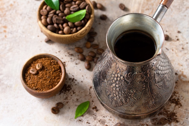 Morning coffee concept turkish coffee in turk and coffee beans\
on a stone or slate countertop