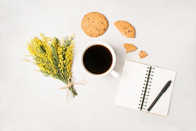 Morning coffee cup clean notebook pencil cookies with chocolate crumbs on white desk overhead view Planning and design concept Cozy breakfast Flat lay styling