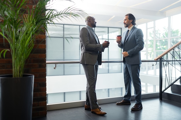 Morning coffee. Dark-skinned businessman drinking coffee with his business partner before having meeting