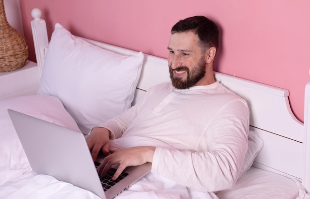 朝のコンセプト 床でラップトップでインターネットに座っているひげの男