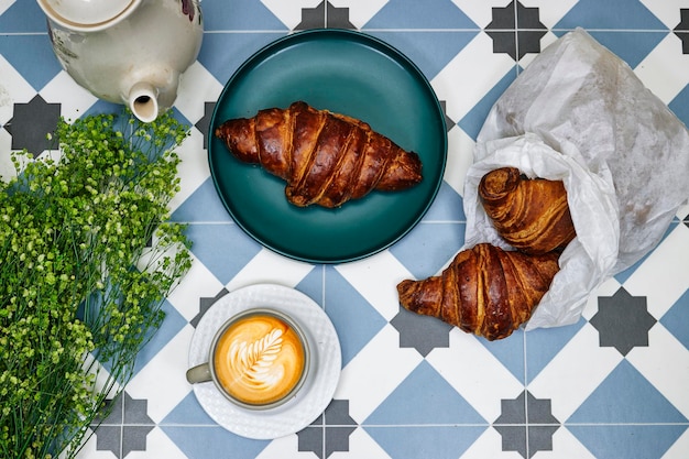 morning concept Fresh baked croissant for breakfast coffee cup with leaf late art on tiles table