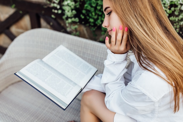 Morning concept. Gorgeous woman reading interesting book while sitting on sofa and relaxing.