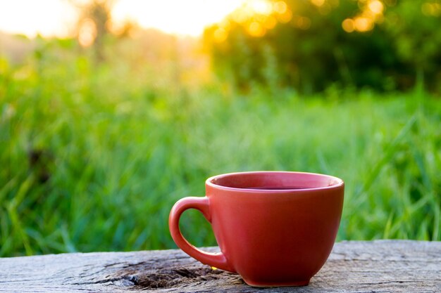 Morning cup of coffee on wooden table at sunrise