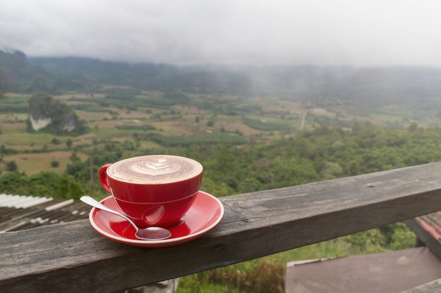 写真 日の出と海で山を背景に木製のテーブルの上のコーヒーの朝カップ