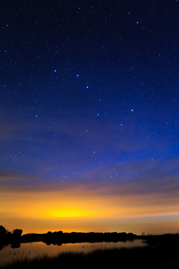 湖の水に映る星空を背景にした朝の夜明け。
