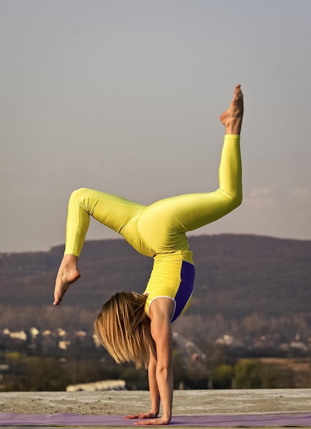 Esercizio mattutino ginnasta nazionale ucraino acrobatica e ginnastica ragazza yoga stretching all'aperto pilates studio online attraente giovane donna sportiva sta lavorando in palestra all'aperto