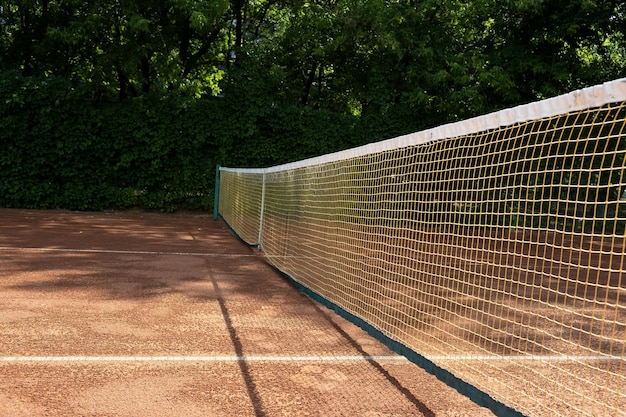 Утро Фрагмент открытого грунтового теннисного корта Видна сетка и линии разметки Спортивный фон.