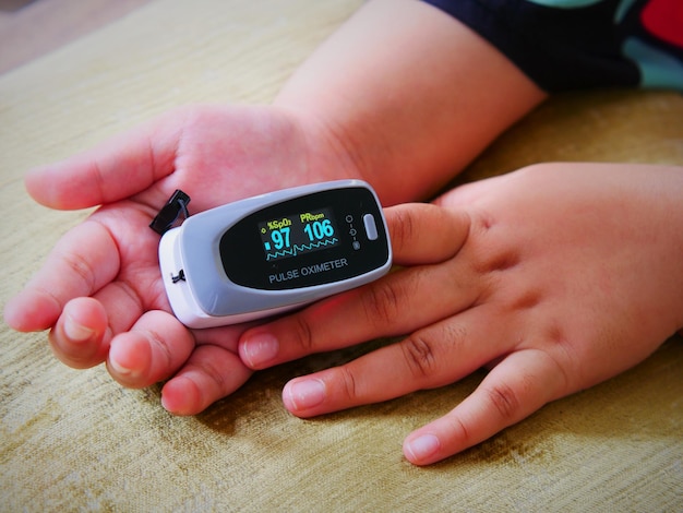 Photo in the morning the girl uses an oxygen and pulse monitor on her index fingertips