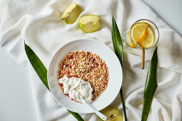 Morning granola breakfast with greek yougurt and glass of detox water