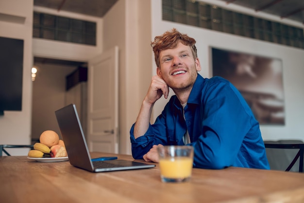 Morning at home. Ginger young man sitting at the table in the kithcen