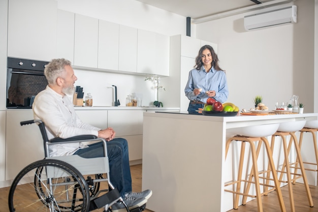 Morning at home. Gray-haired handicapped man and his wife at home before breakfast