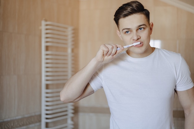 Morning hygiene, the boy brushes his teeth near the mirror