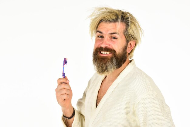Morning inspiration. good morning. male health care and personal hygiene. time to relax. brutal bearded hipster isolated on white. feeling happy in bathroom. man in bathrobe brush his teeth.