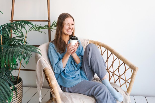 Morning relaxation Girl sits in wicker chair and enjoys coffee in cozy home