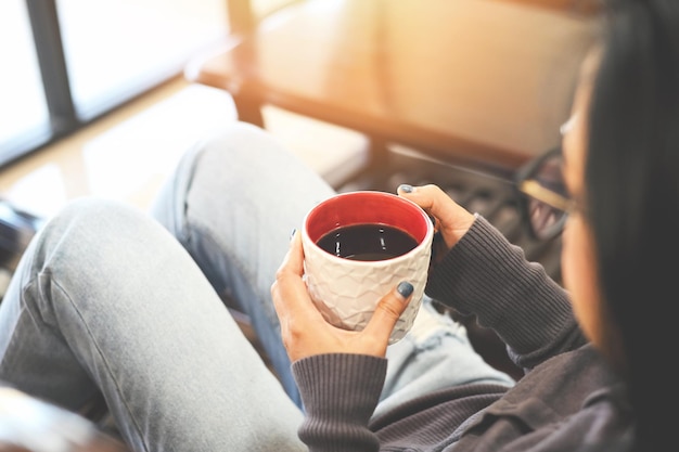 Rilassamento mattutino ragazza seduta e godendosi il caffè tempo libero donna felice che si rilassa a casa in inverno donna che si rilassa a casa e si siede sul divano e guarda bevendo caffè