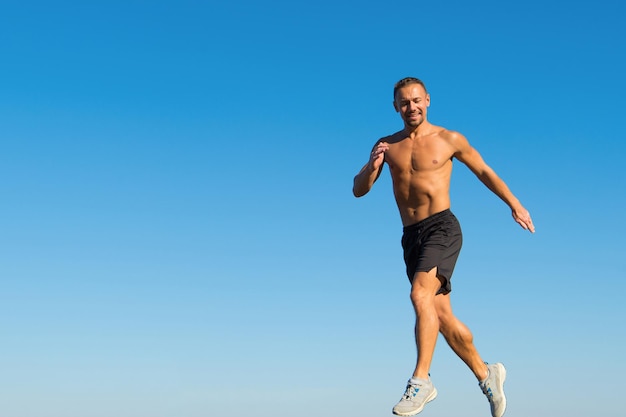 朝のランニングは元気いっぱい。動機と達成。朝の習慣を実行します。ランナーモーション前方空の背景。成功への前進。健康的な生活のための毎日のトレーニング。男アスリートの筋肉の胴体が走ります。