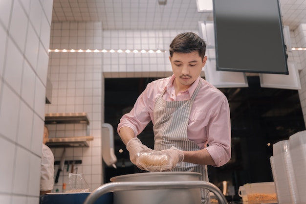 Morning shift. Young hard-working dark-haired worker of kitchen working hard having morning shift