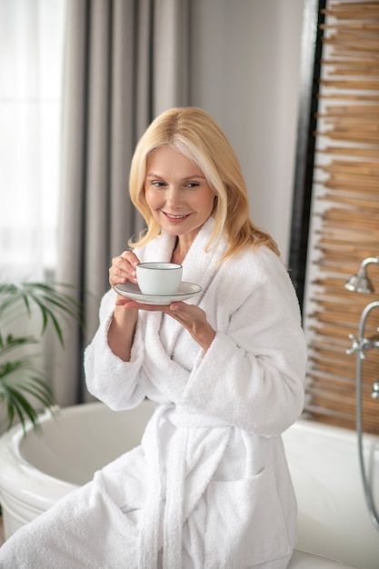 Morning tea. good-looking blonde woman having tea and looking\
balanced