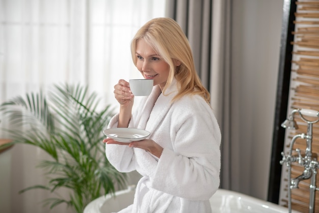 朝のお茶。お茶を飲んでバランスのとれた見栄えの良いブロンドの女性