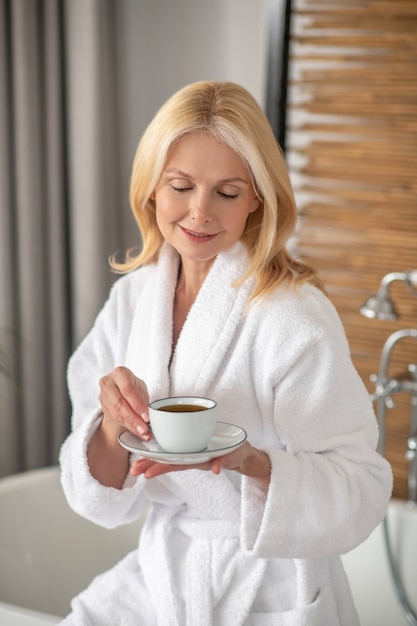 Morning tea. good-looking blonde woman having tea and looking\
balanced