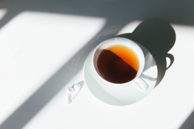 Morning tea on a white table with white earphones.  Clean, quiet and calm morning