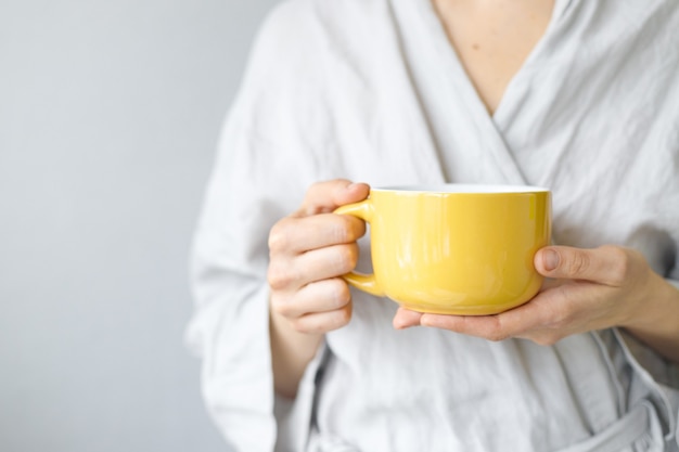 Morning tea with lemon caucasian woman puts lemon in black tea yellow cup