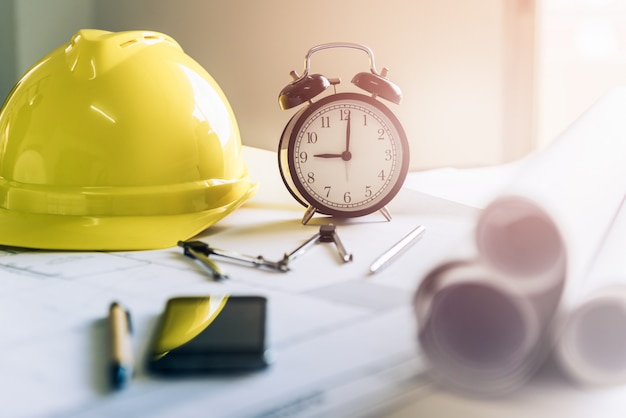 Morning time it's nine o'clock already, A retro clock showing 9:00 am on the desk of engineer designer and architect in an office with equipment and drawing paper for working plan.